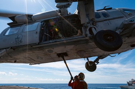 Sailors assigned to weapons department aboard the world's largest aircraft carrier, USS Gerald R. Ford (CVN 78), hook cargo to an MH-60S Sea Hawk, attached to the "Tridents" of Helicopter Sea Combat Squadron (HSC) 9, during a vertical replenishment (VERTREP) on the flight deck, March 27, 2025.