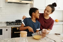 Smiling mother and son stand in kitchen, mixing ingredients in a mixing bowl