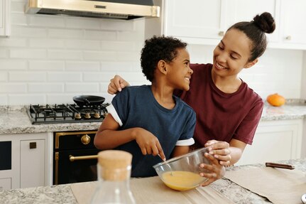 Smiling mother and son stand in kitchen, mixing ingredients in a mixing bowl