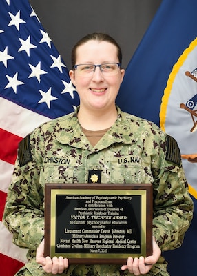 t. Cmdr. Devon Johnston, Military Program Director for NMCCL’s Combined Military-Civilian Psychiatry Residency Program poses with the Victor J. Teichnor plaque.