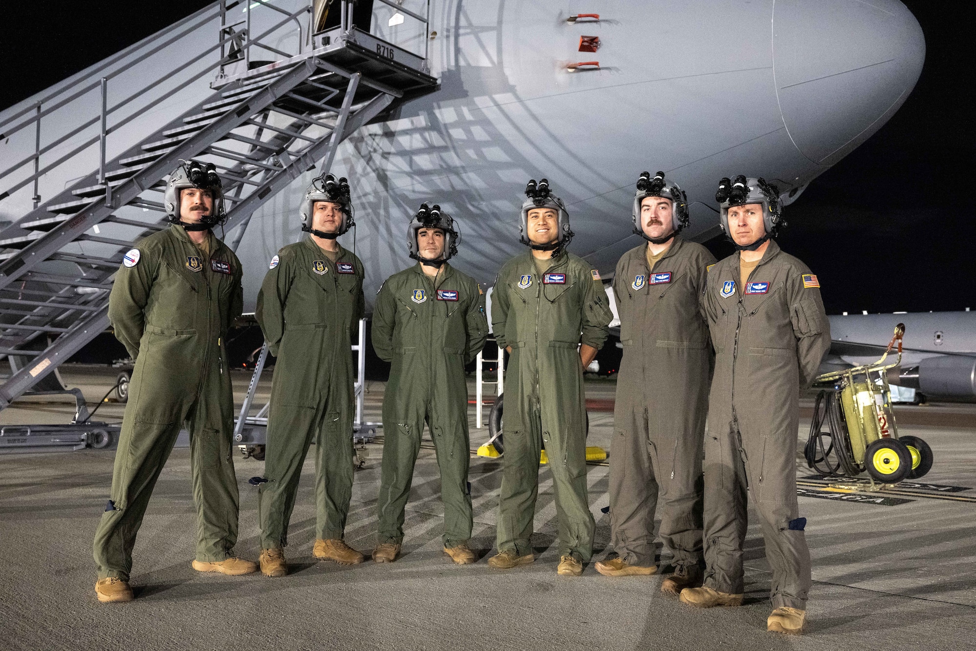 Aircrew standing in front of KC-46 posing for photo with night vision goggles on their heads.