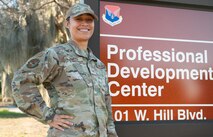 African American female U.S. Air Force Staff Sgt., standing in front of Professional Development center sign.