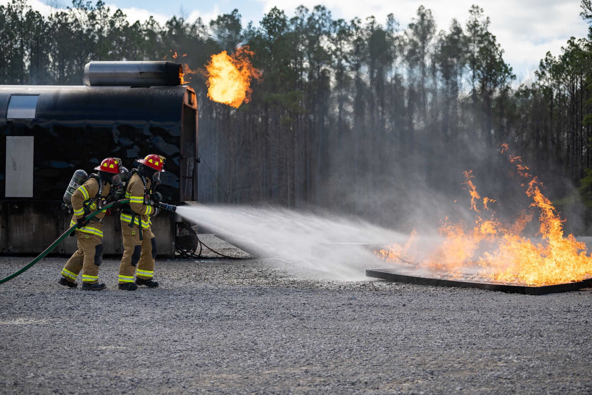 Arnold Engineering Development Complex Commander Col. Grant Mizell, right, attempts to extinguish a simulated aircraft fuel leak fire during live fire training March 6, 2025, at Arnold Air Force Base, Tenn. Mizell is supported by Arnold AFB Fire and Emergency Services Firefighter Crew Chief Kenneth Locker. AEDC is headquartered at Arnold AFB. In early March, Arnold FES conducted live fire training exercises on the base to maintain compliance and enhance emergency response readiness. Training sessions involved the use of a mobile trailer to simulate a residential structure fire and a simulator to emulate interior and exterior aircraft fuselage fires. (U.S. Air Force photo by Keith Thornburgh)