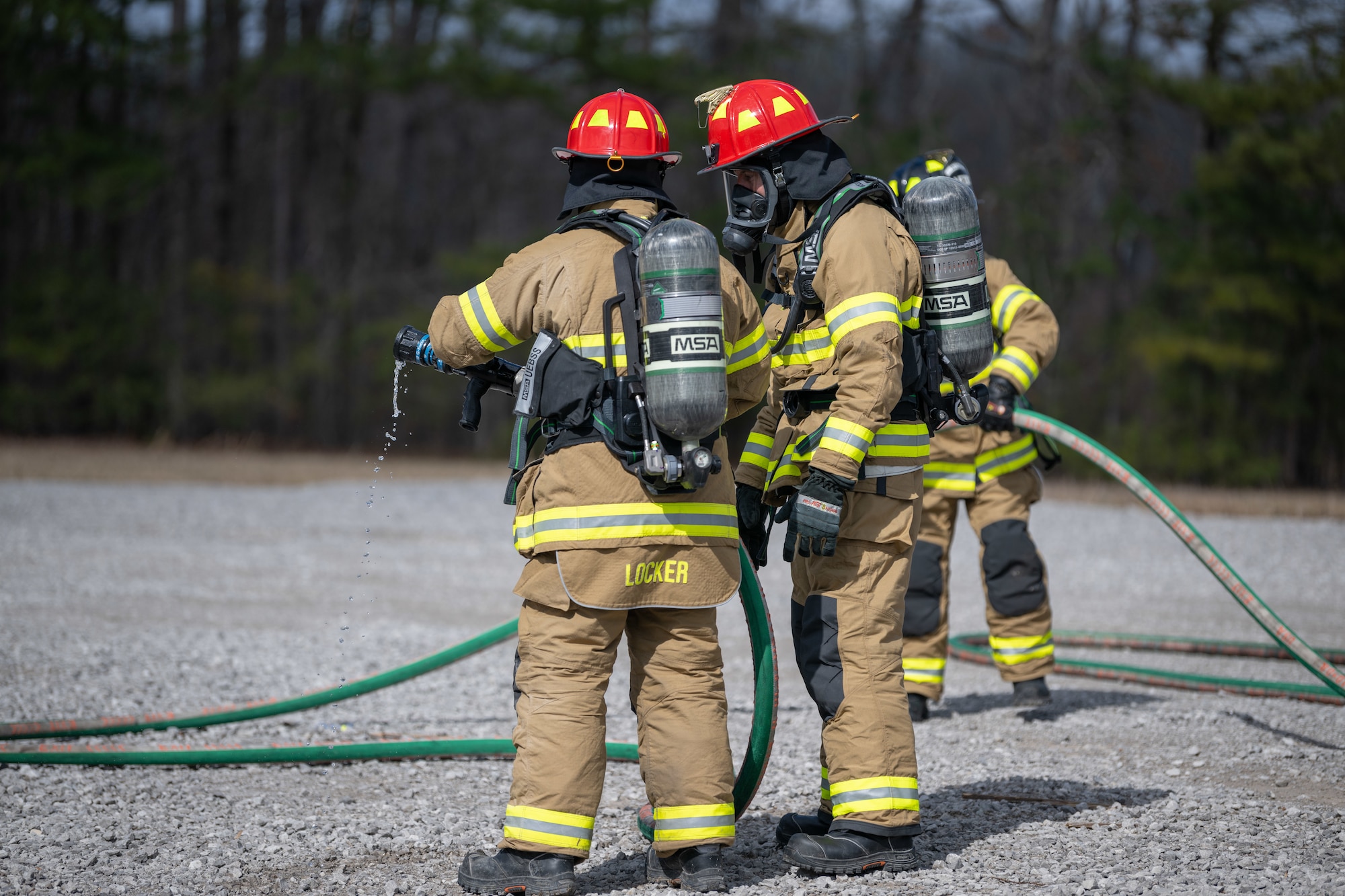 Arnold Air Force Base Fire and Emergency Services Firefighter Crew Chief Kenneth Locker, left, demonstrates firehose usage for Col. Grant Mizell, Arnold Engineering Development Complex commander, during live fire training March 6, 2025, at Arnold AFB, Tenn. AEDC is headquartered at Arnold AFB. In early March, Arnold AFB Fire and Emergency Services conducted live fire training exercises on the base to maintain compliance and enhance emergency response readiness. Training sessions involved the use of a mobile trailer to simulate a residential structure fire and this simulator which emulates interior and exterior aircraft fuselage fires. (U.S. Air Force photo by Keith Thornburgh)