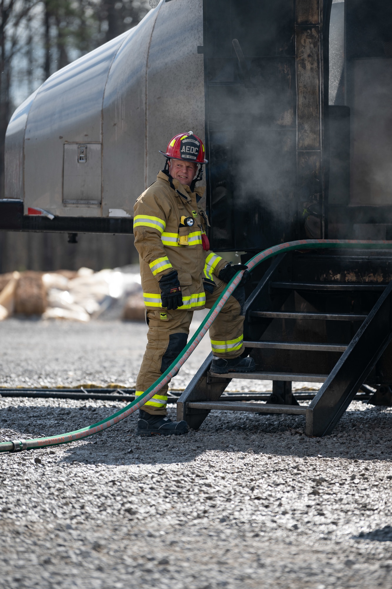 Arnold Air Force Base Fire and Emergency Services Firefighter Crew Chief Kenneth Locker offers handline firefighting support during live fire training on a simulated aircraft fuselage March 6, 2025, at Arnold AFB, Tenn. In early March, Arnold FES conducted live fire training exercises on the base to maintain compliance and enhance emergency response readiness. Training sessions involved the use of a mobile trailer to simulate a residential structure fire and a simulator to emulate interior and exterior aircraft fuselage fires. (U.S. Air Force photo by Keith Thornburgh)