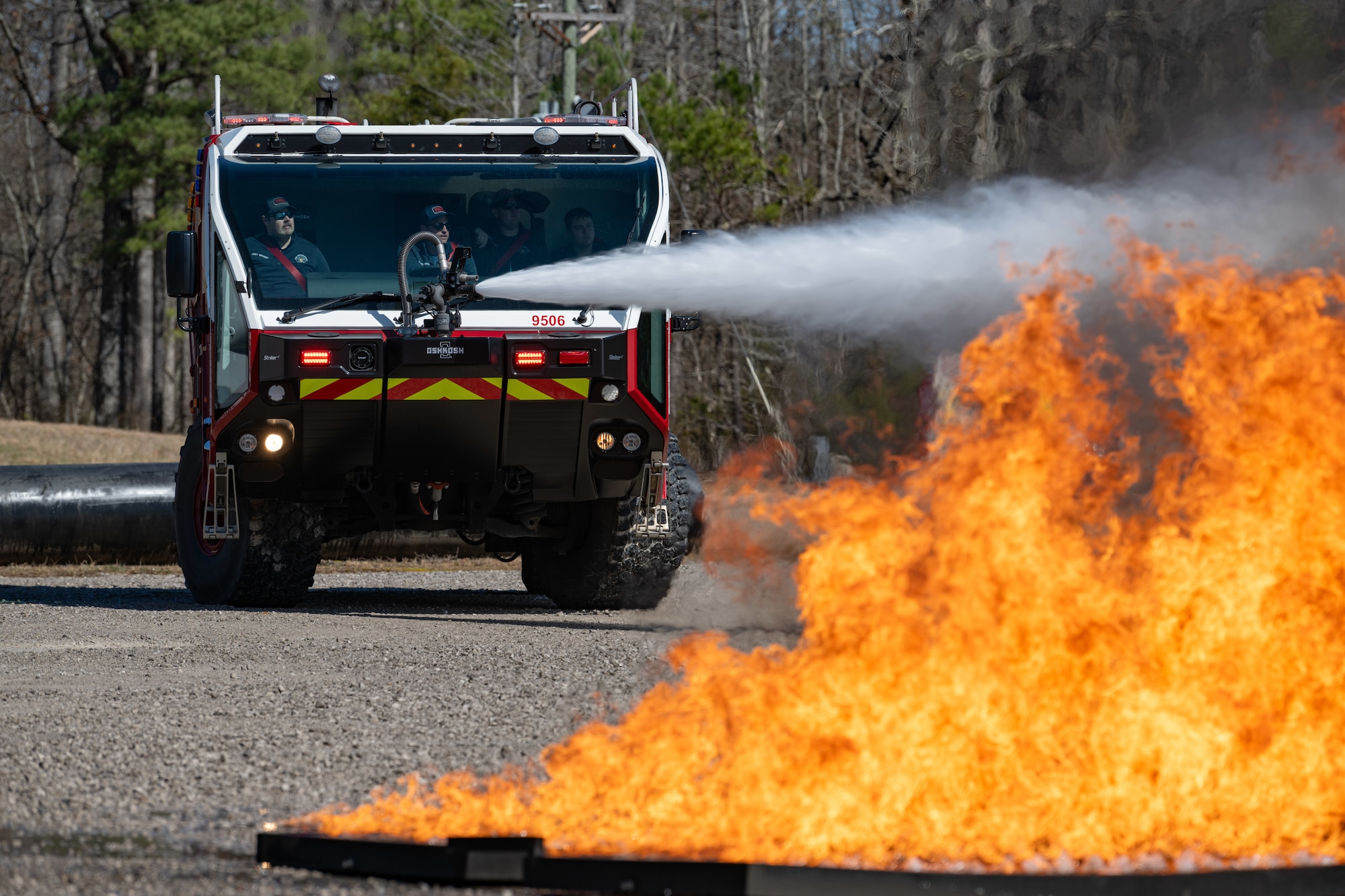An Arnold Air Force Base Fire and Emergency Services P-19 Aircraft Rescue and Fire Fighting truck is used to douse high-pressure water on an exterior aircraft fire during fuselage fire training March 6, 2025, at Arnold AFB, Tenn., headquarters of Arnold Engineering Development Complex. In early March, Arnold FES conducted live fire training exercises on the base to maintain compliance and enhance emergency response readiness. Training sessions involved the use of a mobile trailer to simulate a residential structure fire and a simulator to emulate interior and exterior aircraft fuselage fires. (U.S. Air Force photo by Keith Thornburgh)