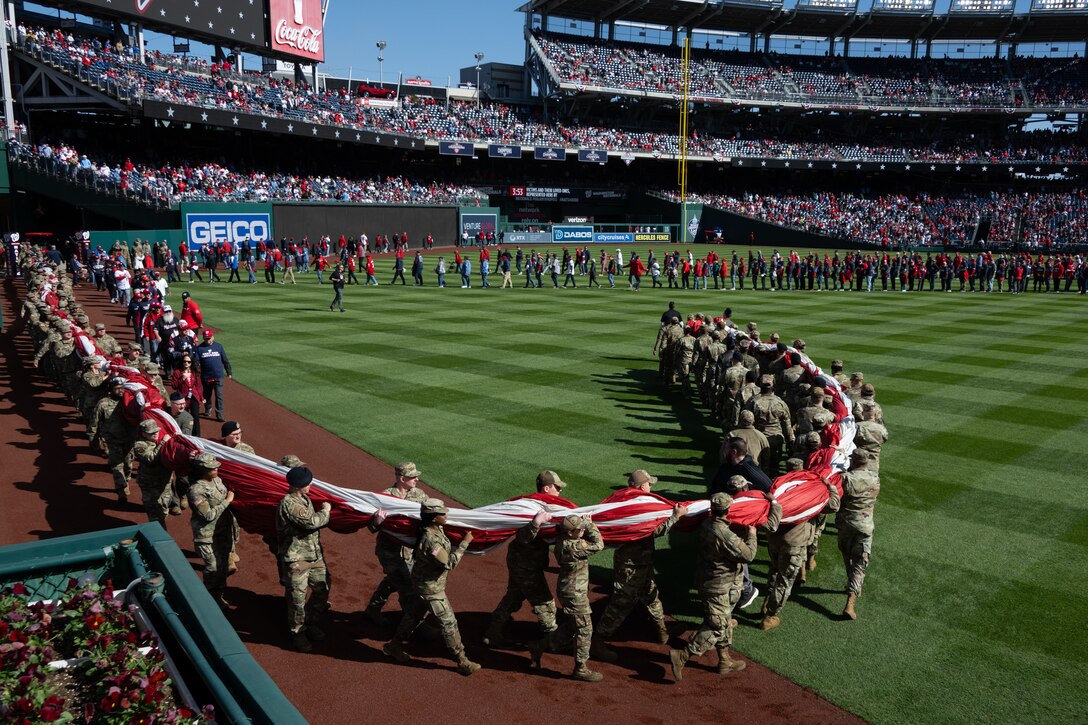 U.S. service members carry the U.S. flag onto the field at Nationals Park during Opening Day.