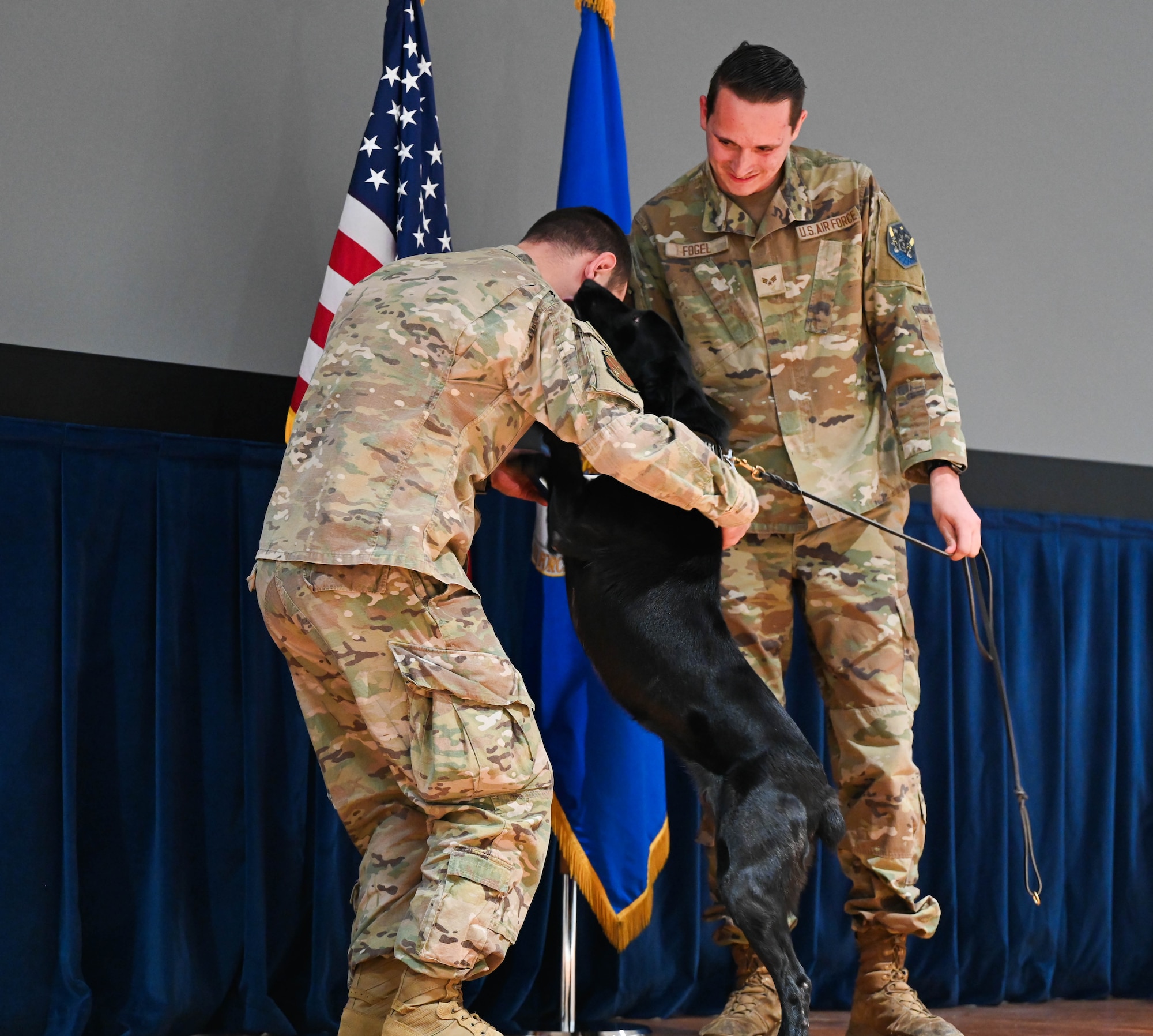 A military member embraces a military working dog on stage