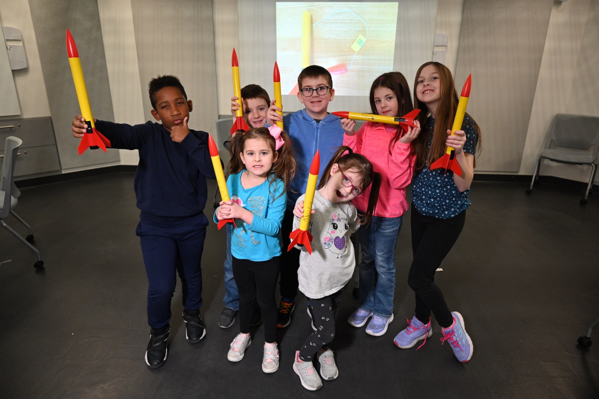 group of youths standing while holding the rockets they just built in the air