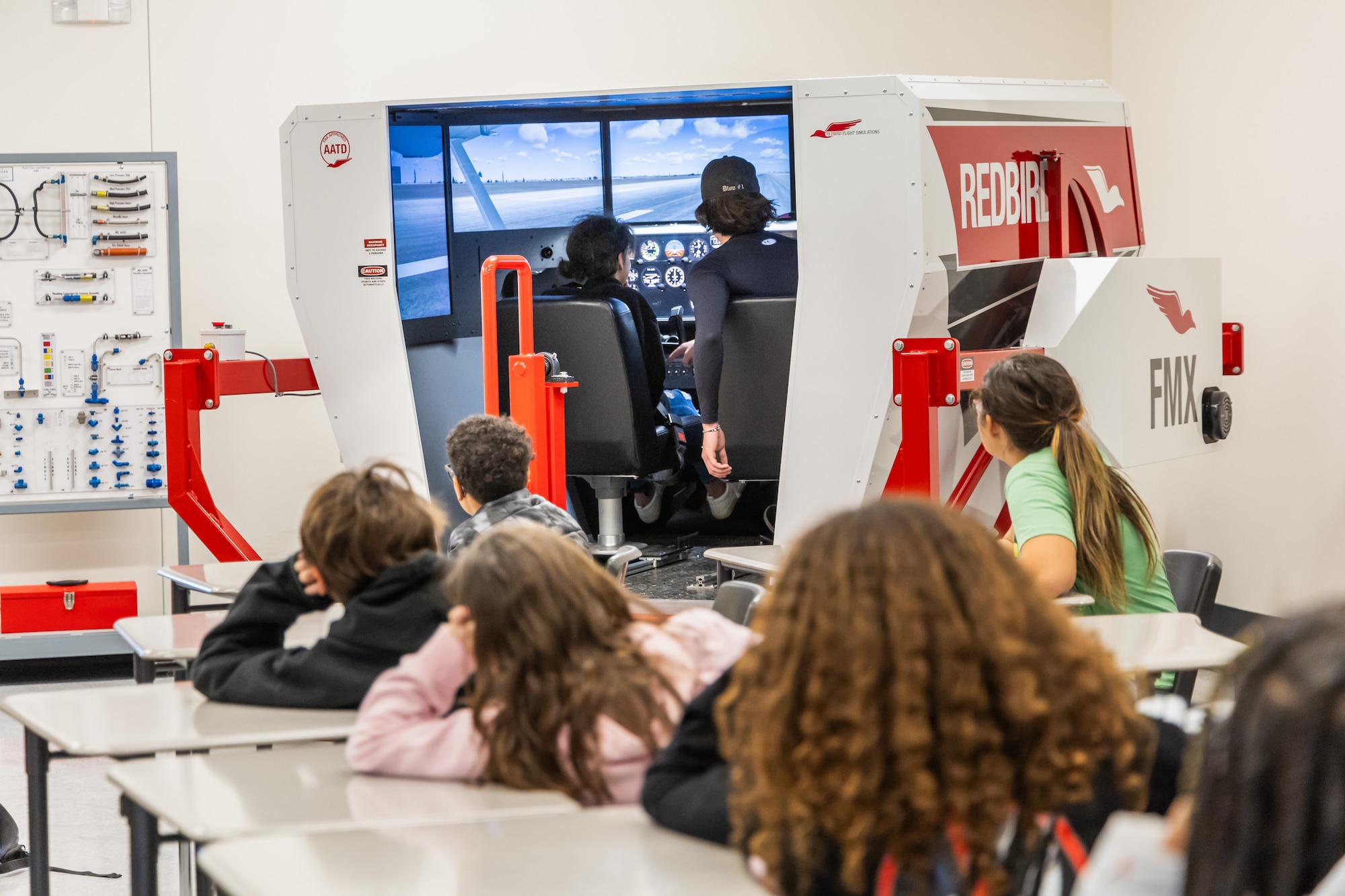 STARBASE students visit the Desert High School Aerospace Lab at Edwards Air Force Base, California. One of the high school students demonstrates the Redbird Flight Simulator to the visitors as they experience some of the opportunities available to them in the future.