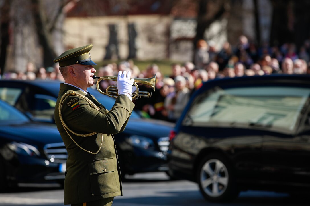 A Lithuanian Armed Forces bugler renders honors during a Dignified Departure to honor fallen U.S. Soldiers