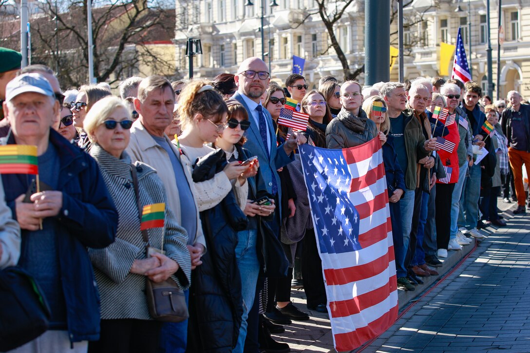 Lithuanian citizens holding an American flag in honor of fall U.S. Soldiers