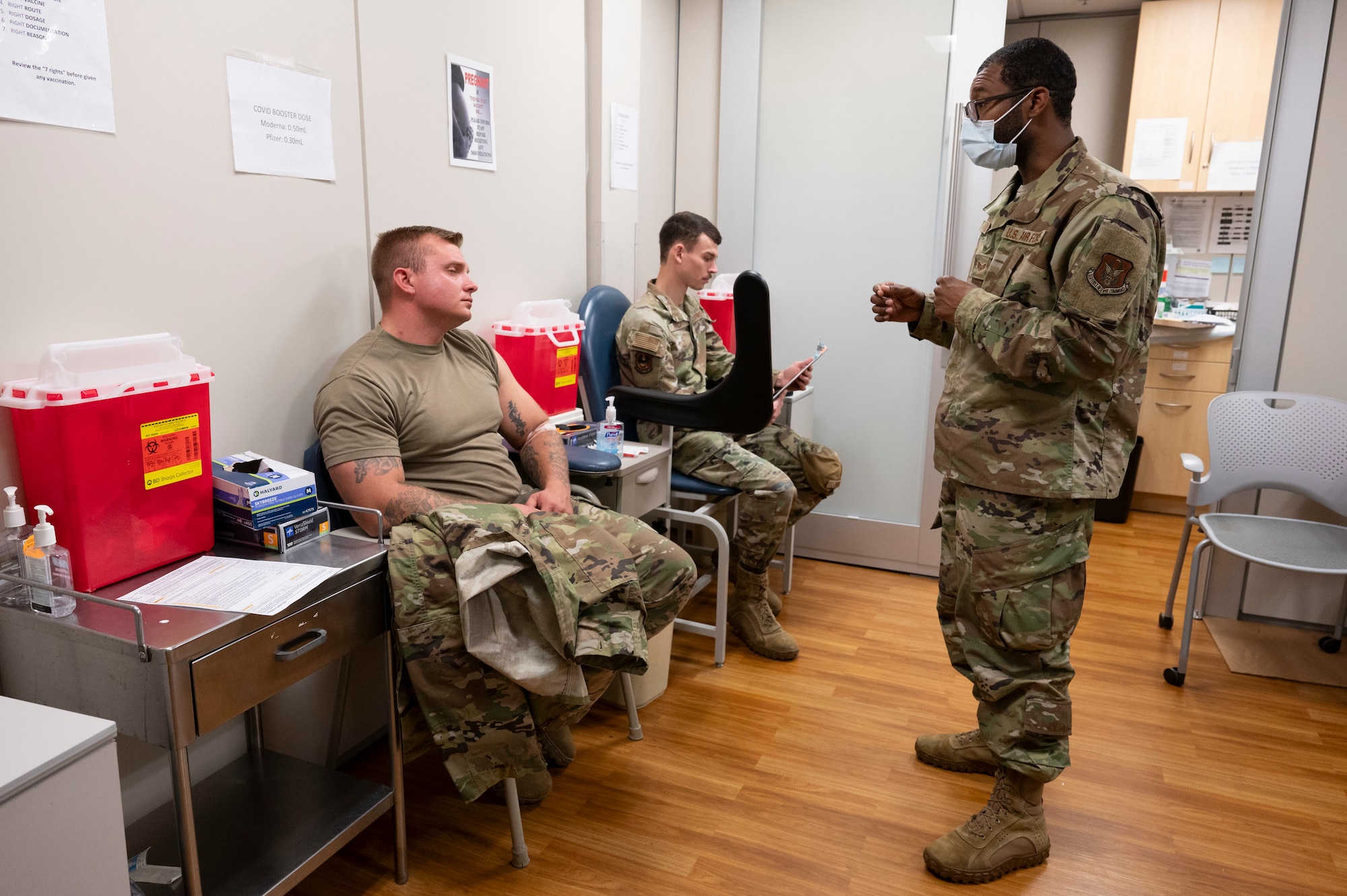 an Airman speaks to another Airman in a medical office