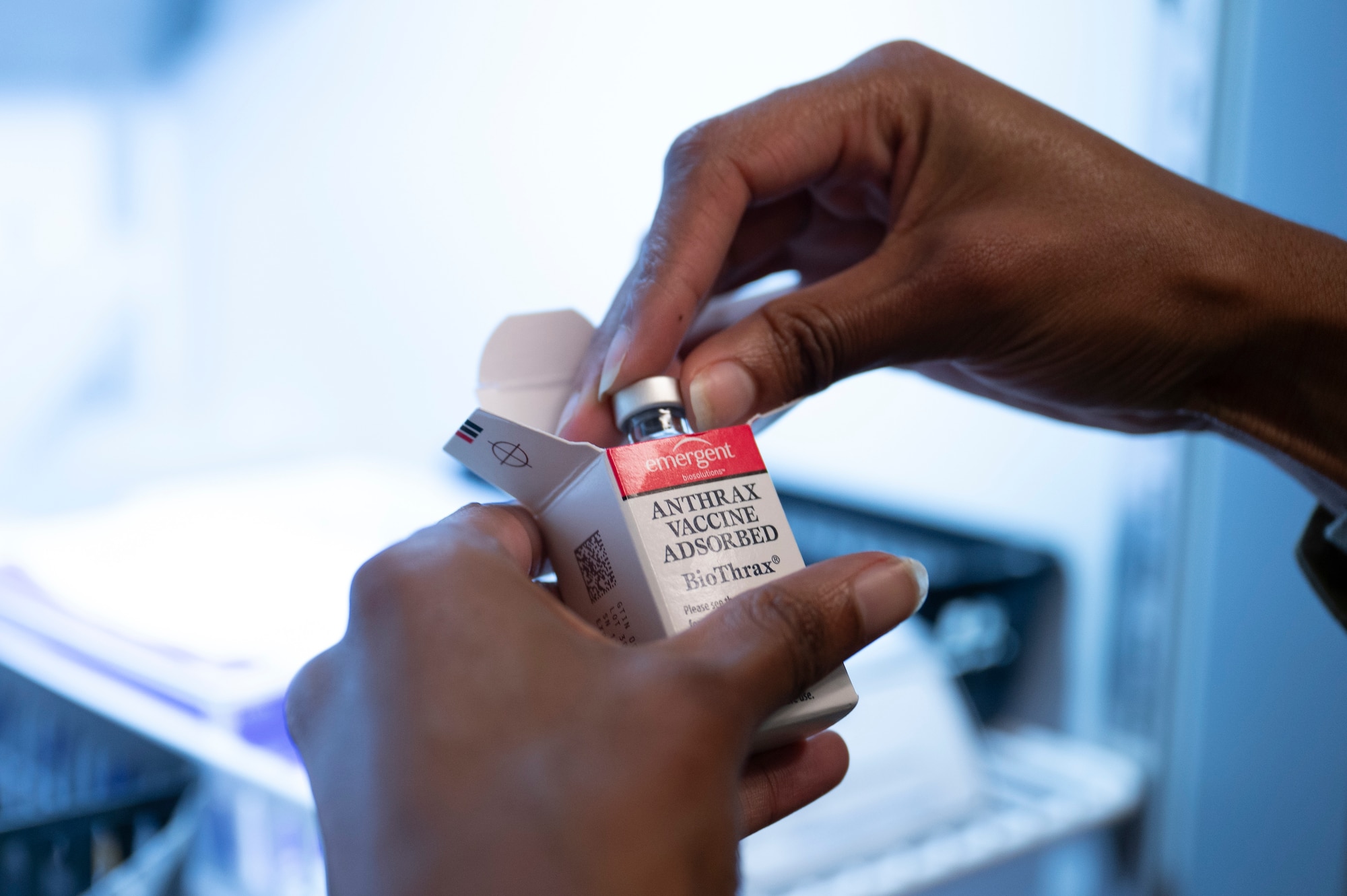 hands grab a vaccine out of a box