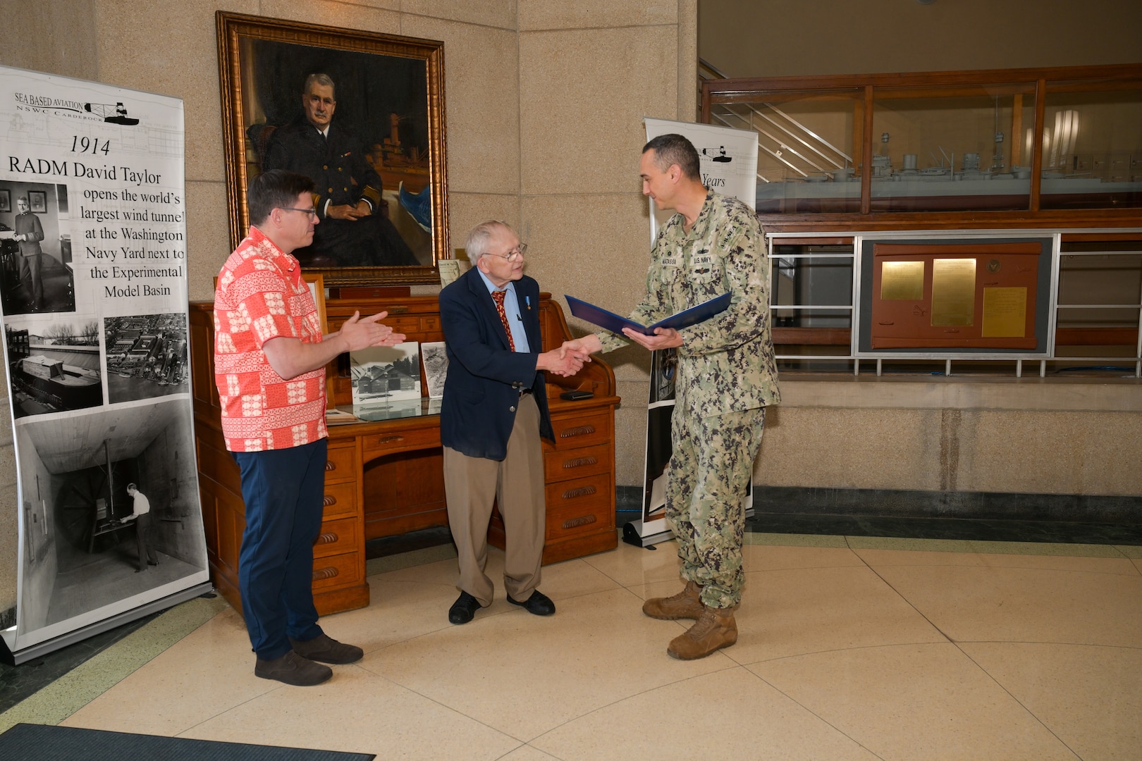 Capt. Christopher Matassa presents Dana Wegner, curator of ship models, with the Department of the Navy Civilian Service Achievement Medal as Dr. David Drazen looks on during Wegner’s retirement ceremony at Naval Surface Warfare Center, Carderock Division, March 21, 2025.