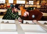 Norfolk Naval Shipyard’s Pipefitter Shop (Shop 56) Pipefitter Mechanic Patrick Douglas (left) and Helper-to-Worker Pipefitter Benjamin Roach work on the pipe assembly cooling system on a jet blast deflector,  a safety device on aircraft carrier flight decks to prevent damage and injury. “We take safety very seriously here in Shop 56. It has to be 100 percent perfect or we don’t sign off on it,” said Douglas. Roach added, “There’s just too much at risk for the Sailors on the flight deck that they need to have the confidence that the jet blast deflectors’ mechanical pieces will not fail them any time during flight operations.”