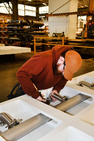 Norfolk Naval Shipyard’s Pipefitter Shop (Shop 56) Helper-to-Worker Pipefitter Benjamin Roach has been at the shipyard for almost two years. He is currently enrolled in the Helper-to-Worker Program, which is a three-year program to learn a specific trade. Before joining NNSY, Roach served in the U.S. Marine Corps for four years. “My primary job in the Marines was finances,” said Roach. “I knew this wasn’t for me, so after my enlistment was over, I joined the Helper-to-Worker Program to learn a trade and to work with my hands and I have no regrets in doing so.”