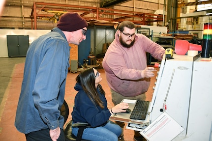 From left to right: Norfolk Naval Shipyard’s Pipefitter Shop (Shop 56) Pipefitter Dominick Bravo, Pipefitter Tammy Davenport and Pipefitter Tyler Bell collaborate while testing a pipe bending machine after receiving updated software.
