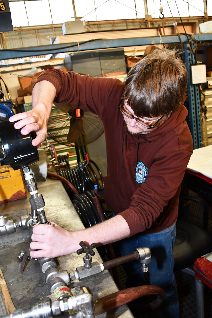 Norfolk Naval Shipyard’s Pipefitter Shop (Shop 56) Pipefitter Philip White is attaching a pressure gauge to a test rig. He is an apprenticeship graduate and has been working at the shipyard for eight years. “I became a pipefitter because I come from a long line of tradesmen and adding pipefitter knowledge expands my family's experience base,” said White.