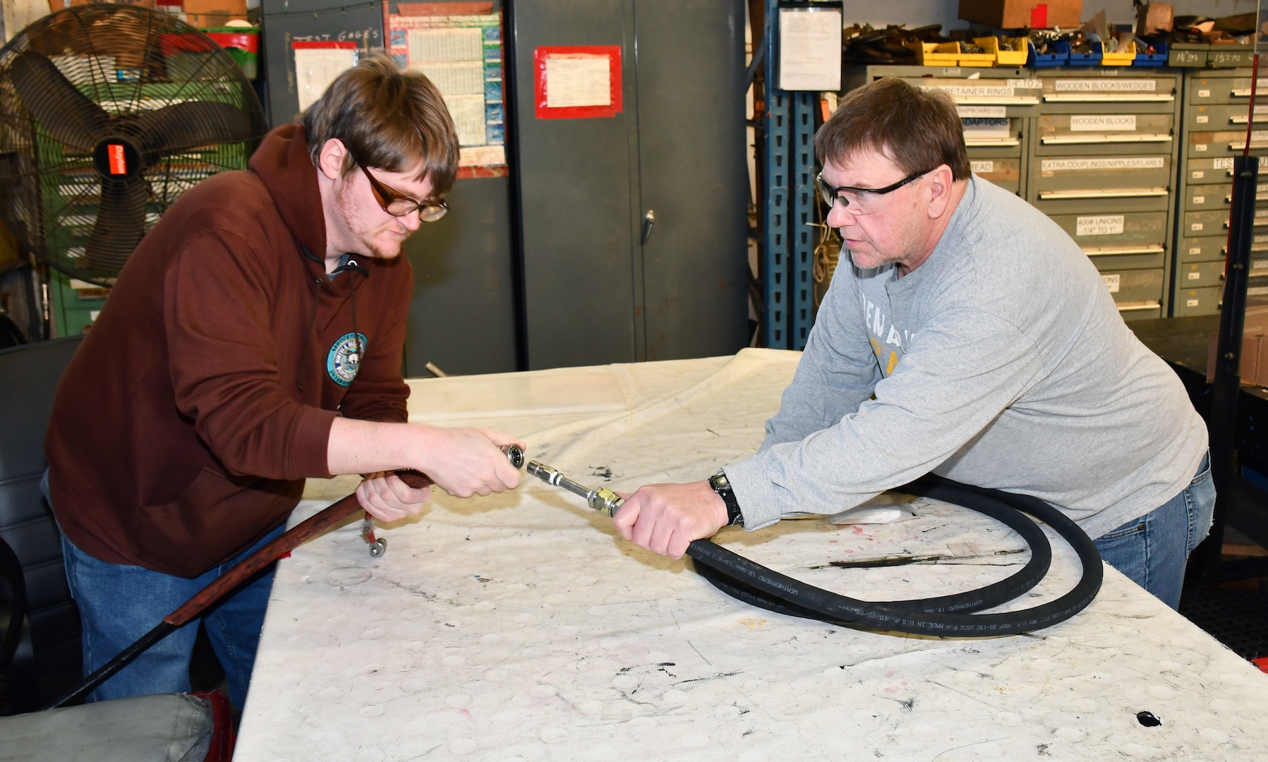 Norfolk Naval Shipyard’s Pipefitter Shop (Shop 56) Pipefitter Philip White (left) and Pipefitter George Sweeney are attaching a hose to a test rig to see if the hose meets all criteria for use. “Our test gang performs testing evolutions on most hoses and piping assemblies before installation on the ship,” said Sweeney.