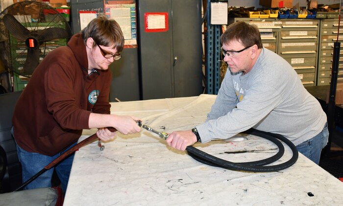 Norfolk Naval Shipyard’s Pipefitter Shop (Shop 56) Pipefitter Philip White (left) and Pipefitter George Sweeney are attaching a hose to a test rig to see if the hose meets all criteria for use. “Our test gang performs testing evolutions on most hoses and piping assemblies before installation on the ship,” said Sweeney.