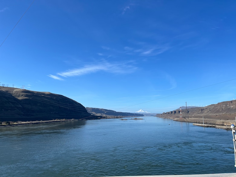 A mountain is in the distance with a river leading up to it with blue skies.