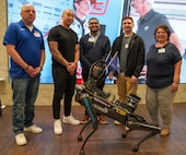 Air Force Captain Capt Joseph Brown, Master Sergeant Nicholas Chung, Airman 1st Class Brandon Marshall, 1st Lt. Michael Ressler, and Irma Blancas from the 688th Cyberspace Wing pose for a group photo at MotoUp's "AI At The Edge" contest.