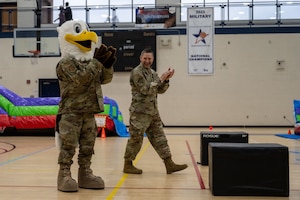 An eagle mascot applauds with a uniformed member