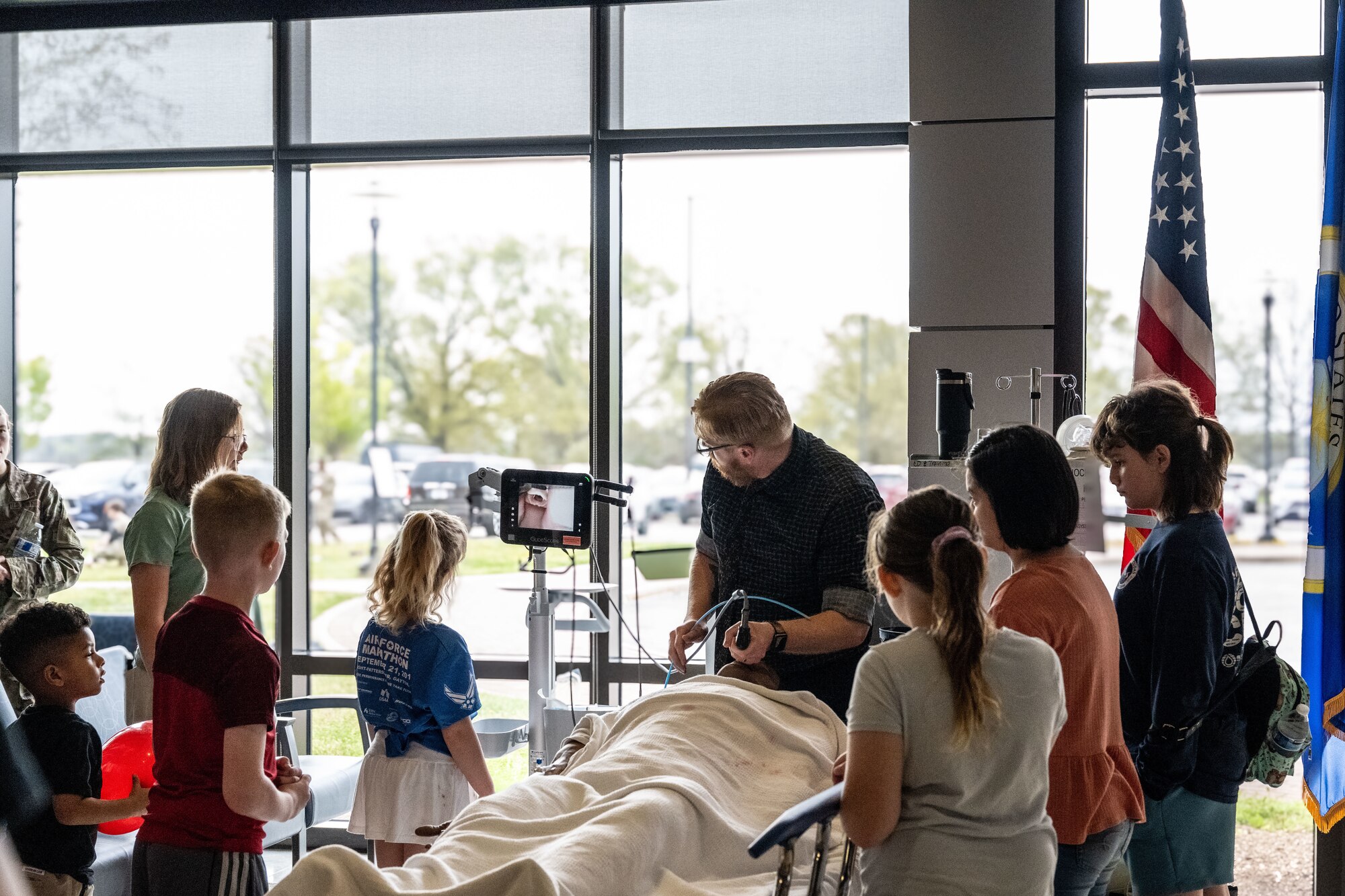 A group of children watch as a man holds a tube.