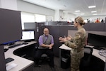 Stephen Shaw, a DLA Land and Maritime procurement analyst, fields questions from colleague Army Maj. Emille Prosko April 2 about robotic process automation.