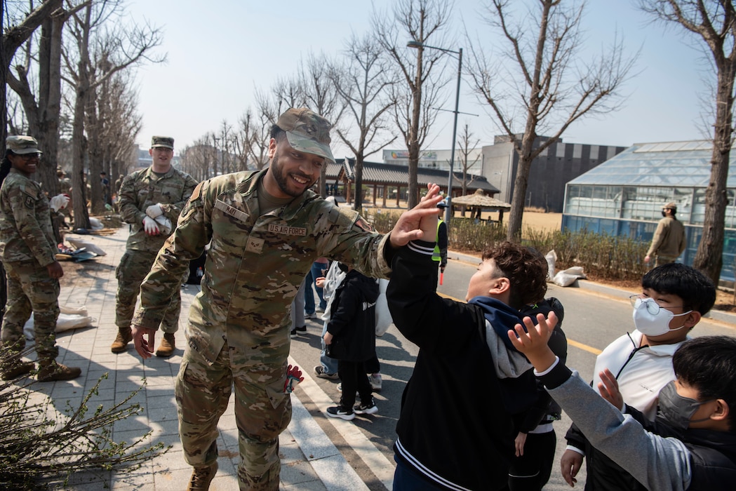 A U.S. Airman assigned to the 51st Fighter Wing high-fives students of a local school after helping them plant trees during the 80th Arbor Day event in Pyeongtaek, Republic of Korea, March 31, 2025.