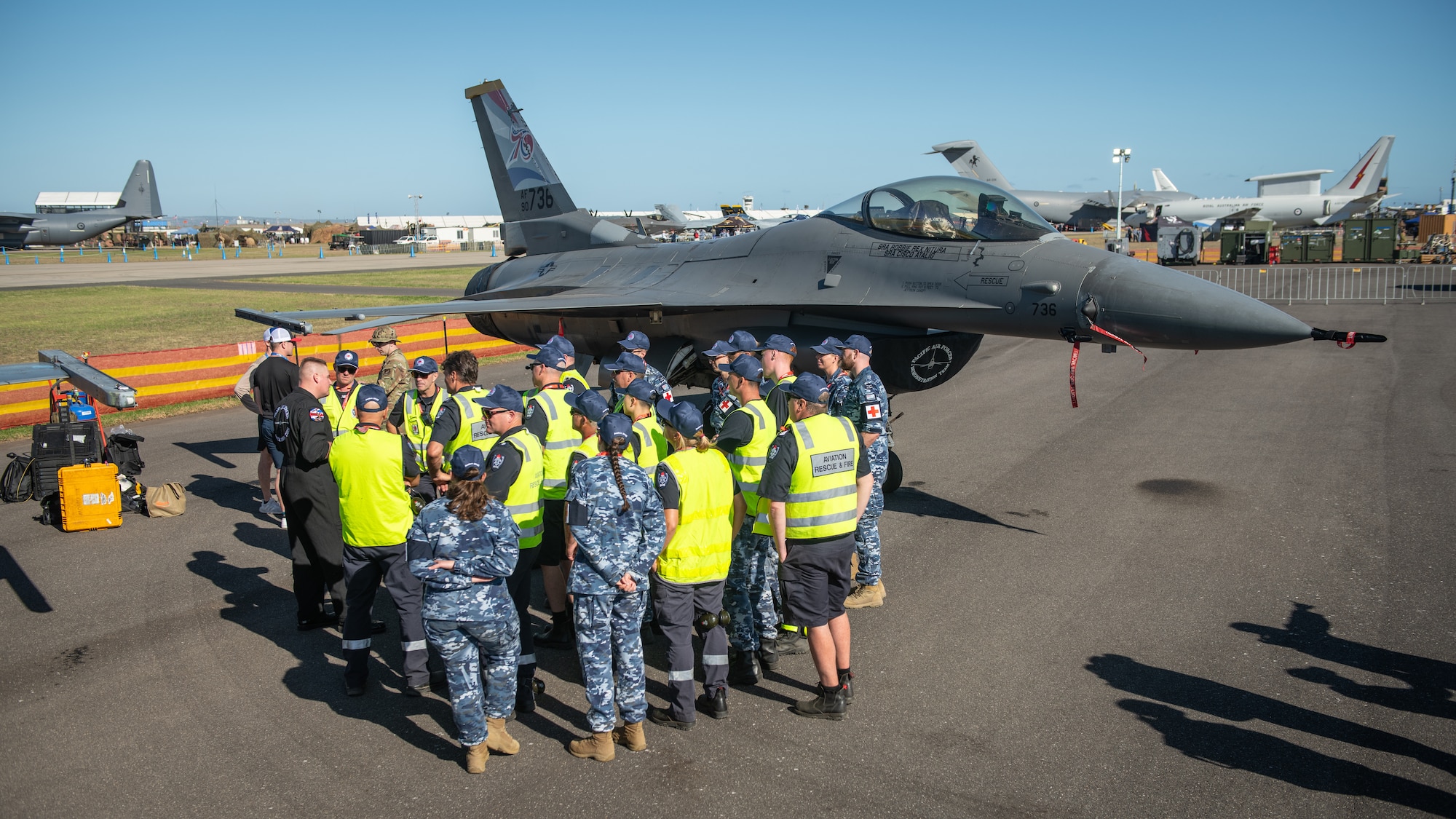 Australian service members listen to crew chief brief about fighter jet