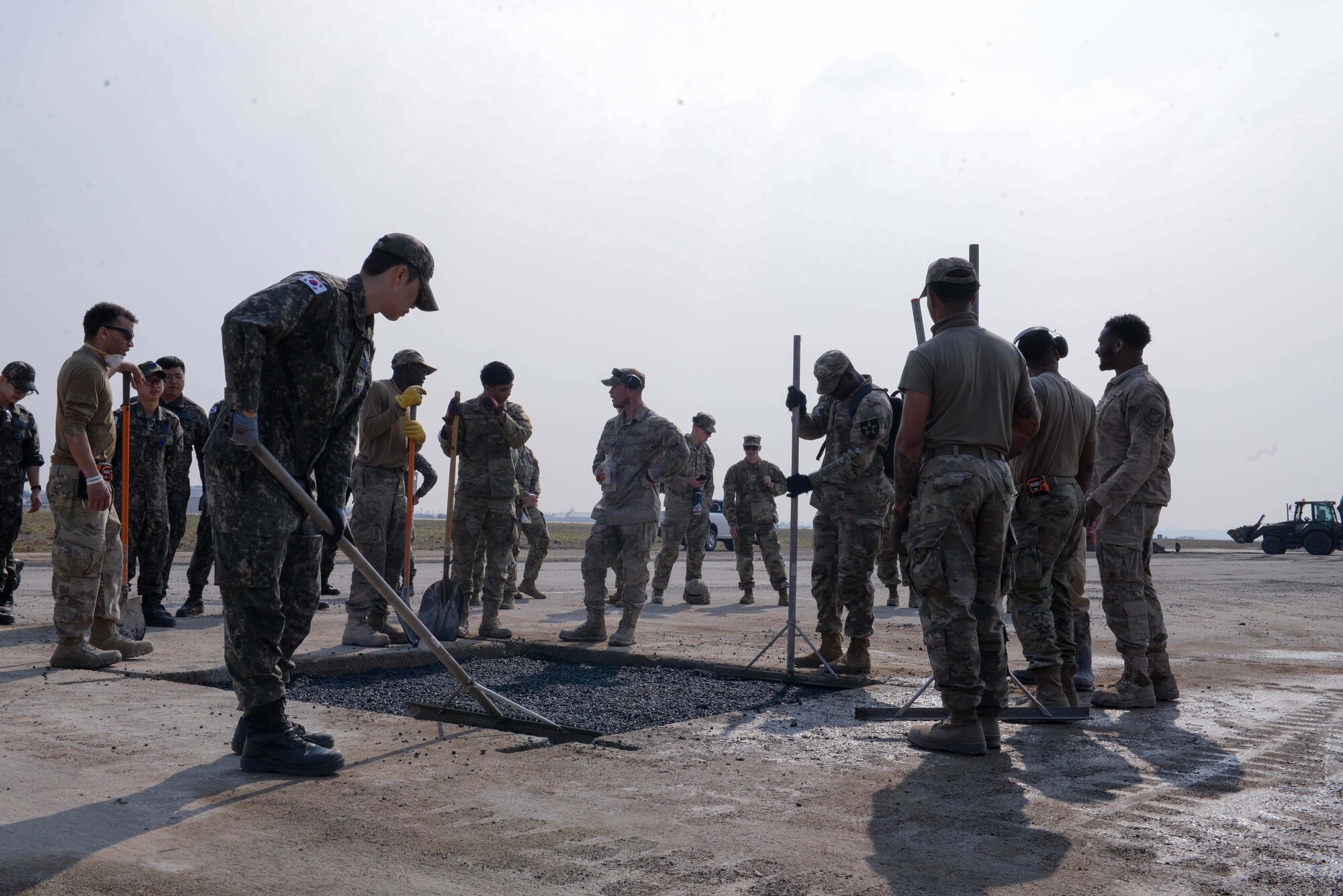Service members assigned to the U.S. Air Force, U.S. Army, and Republic of Korea Air Force level freshly poured asphalt while rapidly repairing a simulated crater at Osan Air Base, Republic of Korea, April 3, 2025. The repairs were part of an instructional and hands-on rapid airfield damage repair training. RADR is a quick process used to repair various structural damages on an airfield in less time, swiftly restoring combat airpower generation at a moment’s notice. (U.S. Air Force photo by Staff Sgt. Kahdija Slaughter)