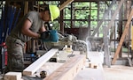 U.S. Air Force A1C Rafael Herrera, power production, cuts wood while working on the framing for the Tama Hills Restoration Project for Yokota Air Base Boy Scouts.