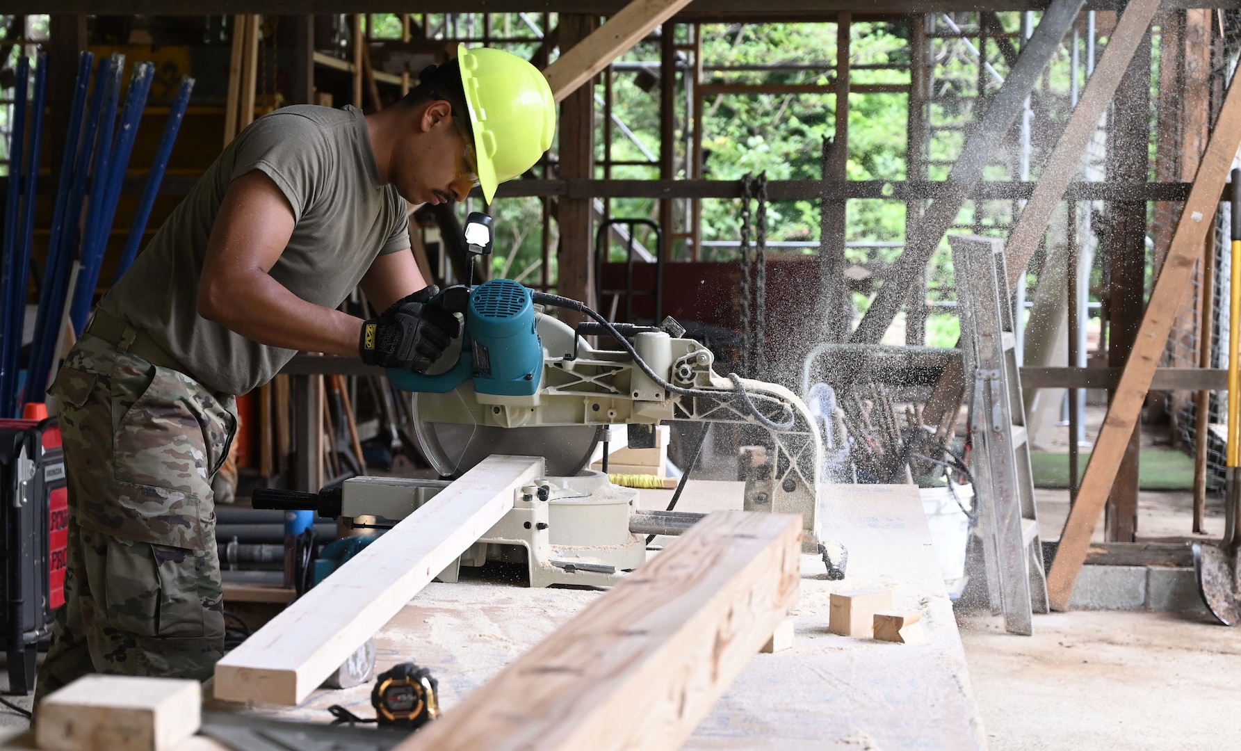 U.S. Air Force A1C Rafael Herrera, power production, cuts wood while working on the framing for the Tama Hills Restoration Project for Yokota Air Base Boy Scouts.