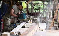 U.S. Air Force A1C Rafael Herrera, power production, cuts wood while working on the framing for the Tama Hills Restoration Project for Yokota Air Base Boy Scouts.