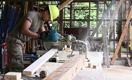 U.S. Air Force A1C Rafael Herrera, power production, cuts wood while working on the framing for the Tama Hills Restoration Project for Yokota Air Base Boy Scouts.