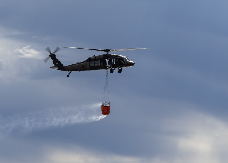 Military helicopter carries water in underslung water bucket