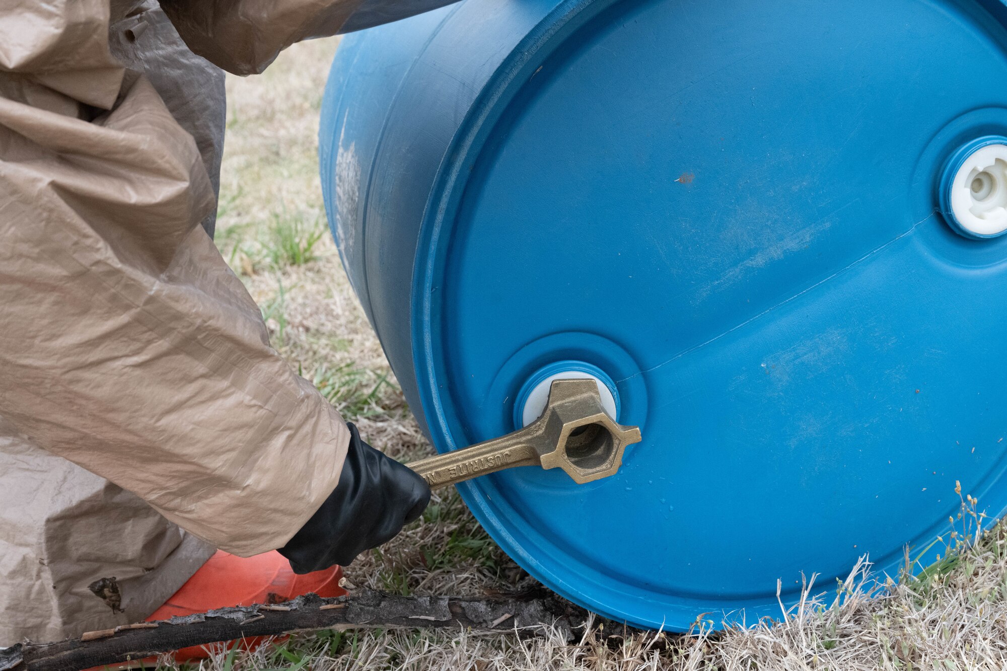 An Airman assigned to the 22nd Medical Group tightens the lid on a container of simulated hazardous material at McConnell Air Force Base, Kansas, March 28, 2025. A blue plastic 55-gallon drum is typically used to store liquid chemicals and solvents. (U.S. Air Force photo by Airman 1st Class Patrick O’Neill)