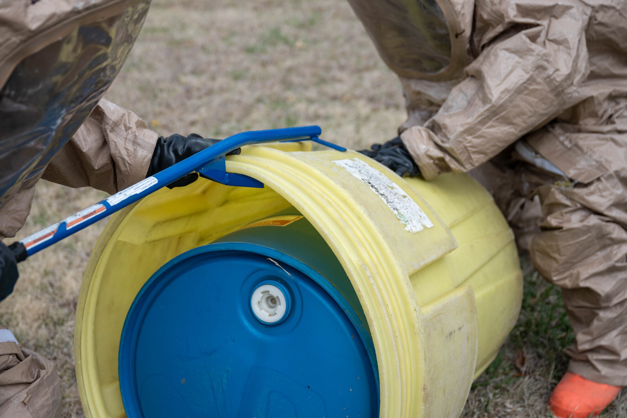 Two Airmen assigned to the 22nd Medical Group stand up an overpacked container of simulated hazardous material at McConnell Air Force Base, Kansas, March 28, 2025. Leaking containers often need reinforcement by an outer layer known as an overpack to contain the material. (U.S. Air Force photo by Airman 1st Class Patrick O’Neill)