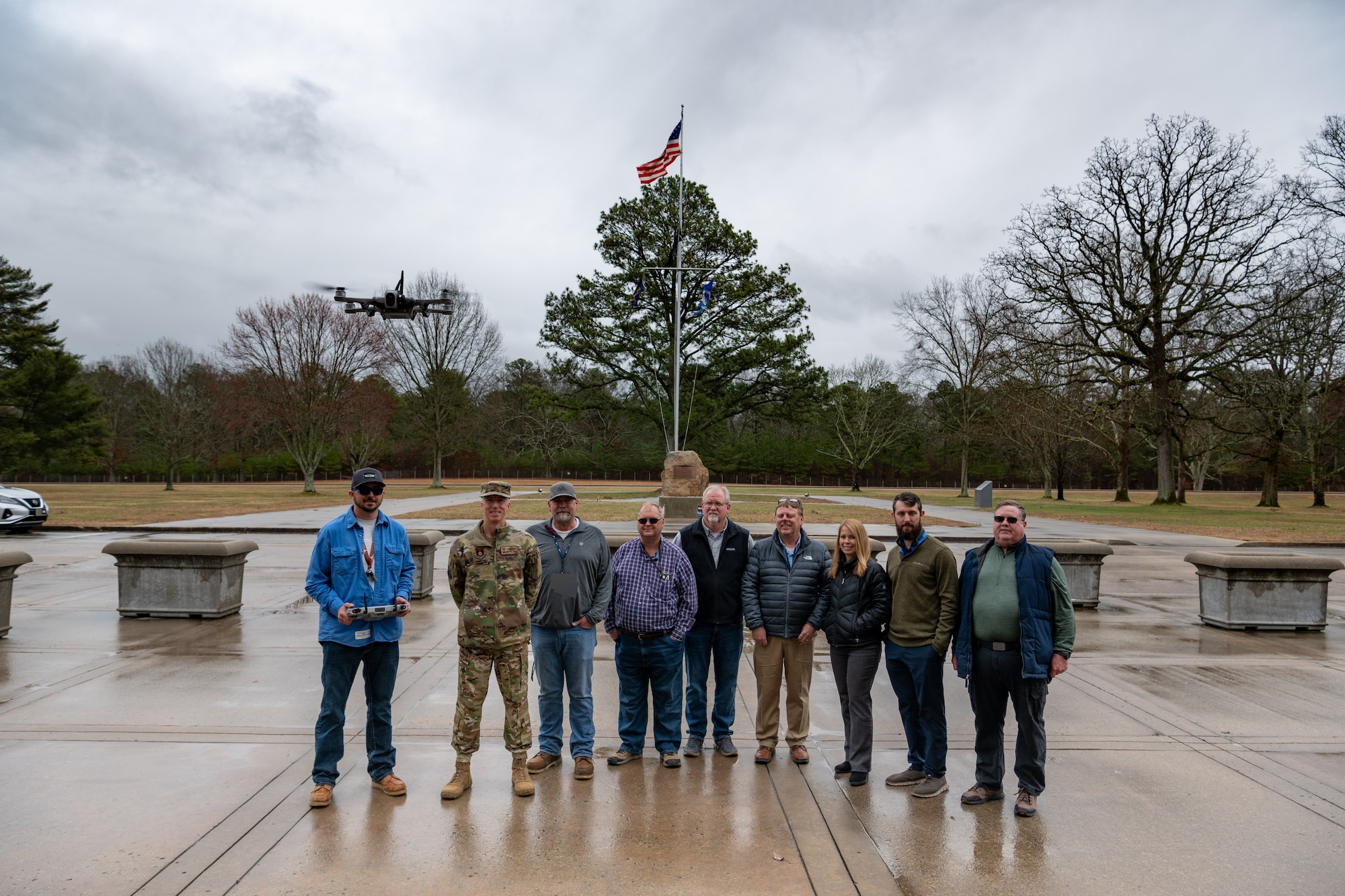 Those who coordinated and observed the March 5, 2025, demonstration of a Small Unmanned Aircraft System, also known as an sUAS or a “drone,” gather for a photo at Arnold Air Force Base, Tenn. Pictured from left are Robert Hastings, Arnold Engineering Development Complex Commander Col. Grant Mizell, Matt Holder, Dan Henley, James Mansfield, Don Brandt, Donna Spry, Pearson Brock and Mike Glennon. AEDC is headquartered at Arnold AFB. The sUAS will soon be used at Arnold to perform asset health assessments. The device is equipped with both digital and infrared imaging capabilities and will be flown around installation buildings, plant facilities and associated equipment to ensure there are no compromises to such assets and to assess the structural integrity of facilities. (U.S. Air Force photo by Keith Thornburgh) (This image was altered by obscuring badges for security purposes)