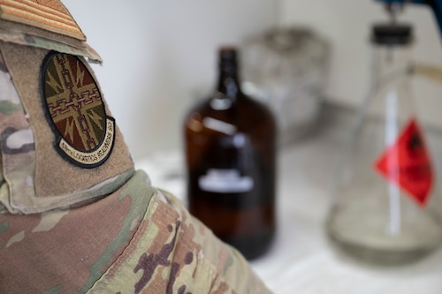 Airman works with science equipment in background.
