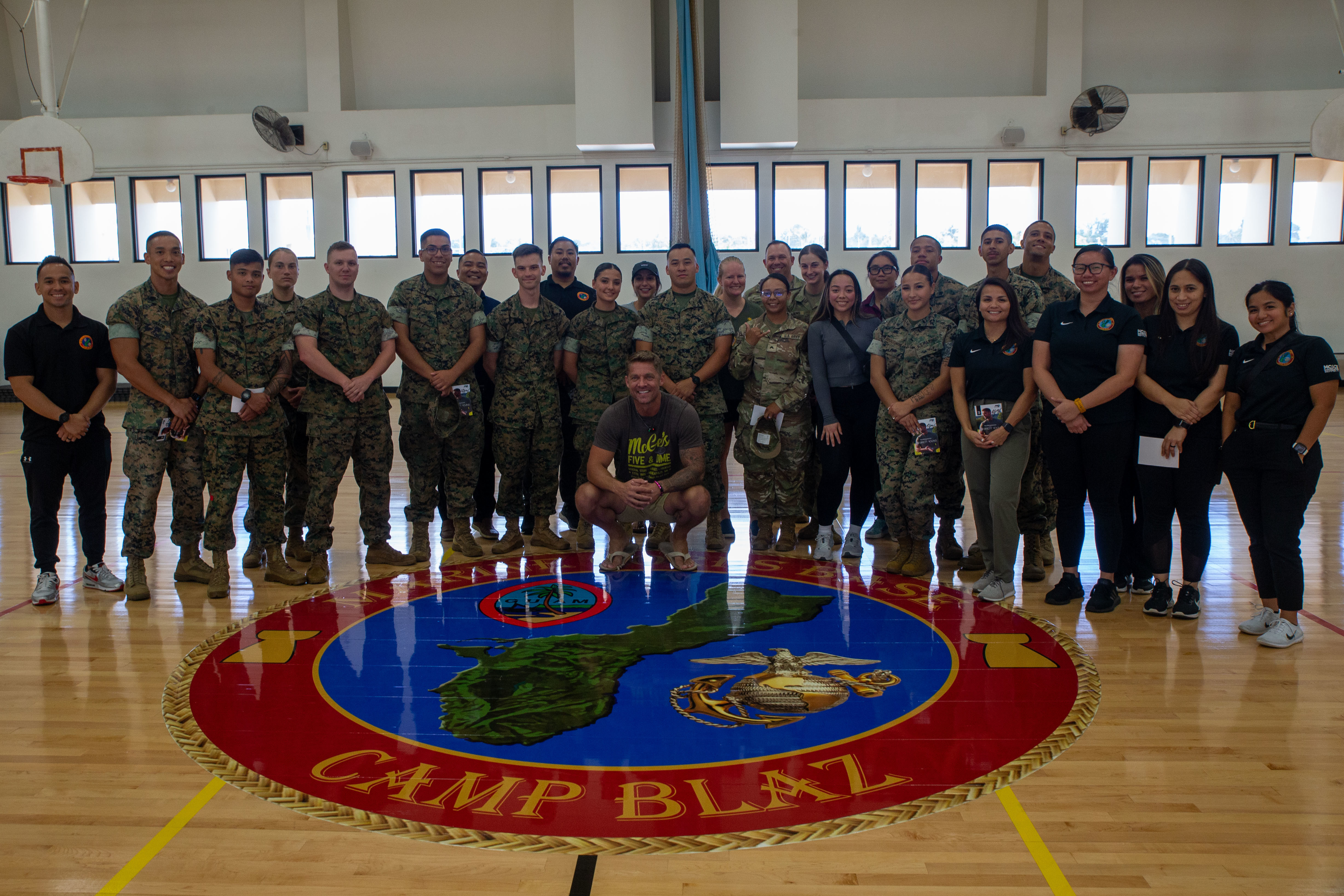 U.S. service members and Marine Corps Base Camp Blaz staff pose for a group photo with country singer, Brett Young, on MCB Camp Blaz, Guam, April 1, 2025. Brett Young is visiting Guam to interact with the service members of the island and perform multiple shows over the duration of his trip.  (U.S. Marine Corps photo by Lance Cpl. Afton Smiley)