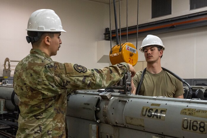U.S. Air Force Airman 1st Class Rodrigo Reyes, left, and Airman Cameron DeGray, 35th Maintenance Squadron avionics flight electronic warfare systems technicians, lower an AN/ALQ-184 electronic countermeasures pod.