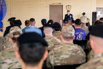 Military member speaks at the podium in front of crowd at building dedication ceremony