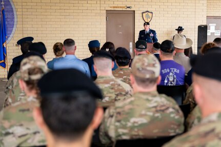 Military member speaks at the podium in front of crowd at building dedication ceremony