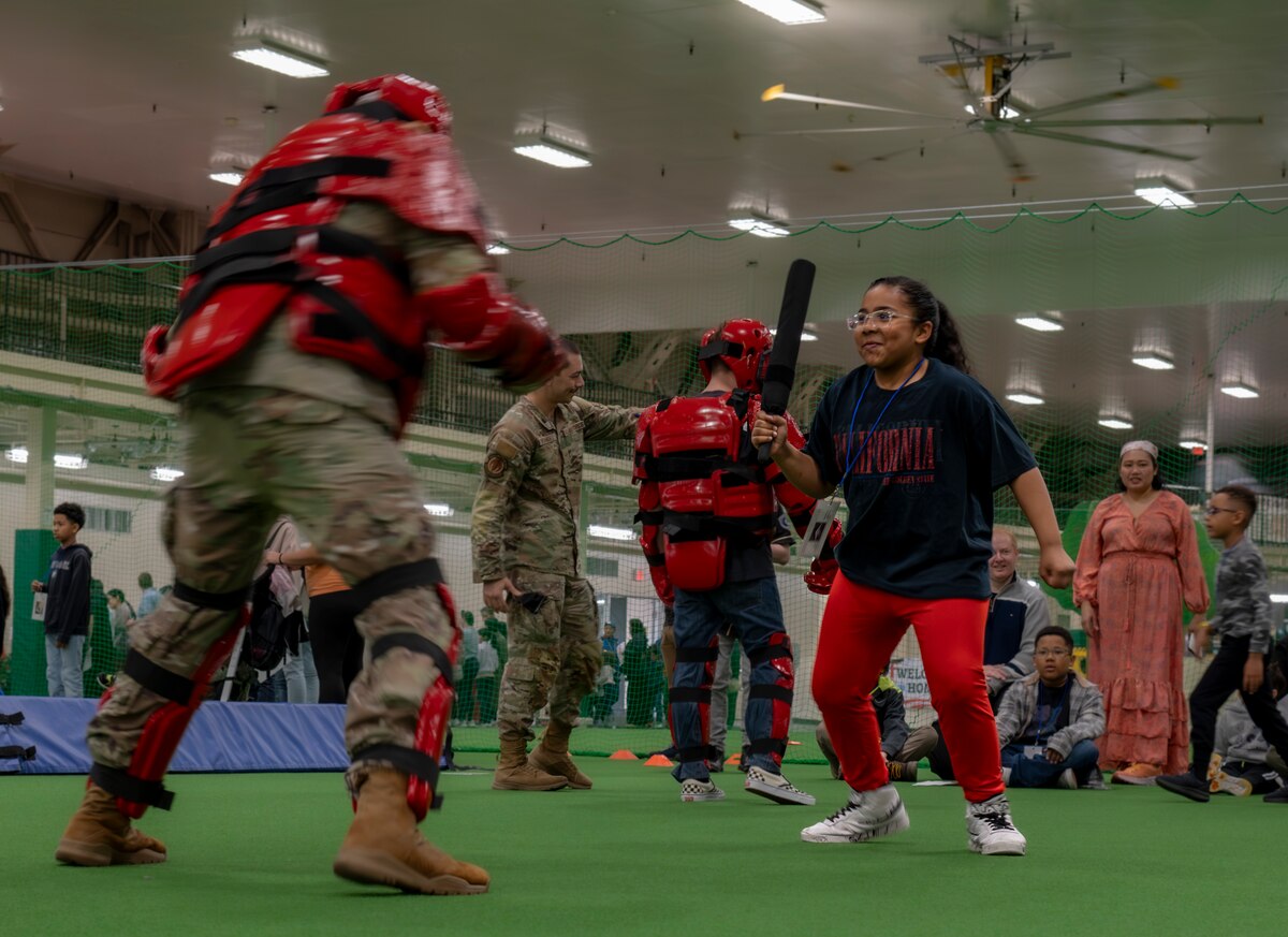 An Operation CODE (Children on Deployment Exercise) participant practices “Red Man” riot control training with a U.S. Air Force Airman assigned to the 35th Fighter Wing (FW) at Misawa Air Base, Japan, April 5, 2025. Operation CODE allows children to go through modified pre-deployment training, bringing families together, building resilience and fostering a sense of connection among the 35th FW. (U.S. Air Force photo by Senior Airman Brittany Russell)