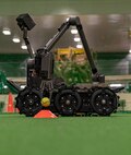 A Man Transportable Robot System places a tennis ball on a cone during Operation CODE (Children on Deployment Exercise) at Misawa Air Base, Japan, April 5, 2025. This hands-on demonstration allowed children of the 35th Fighter Wing to see how advanced technology supports safety and precision in real-world operations. (U.S. Air Force photo by Senior Airman Brittany Russell)