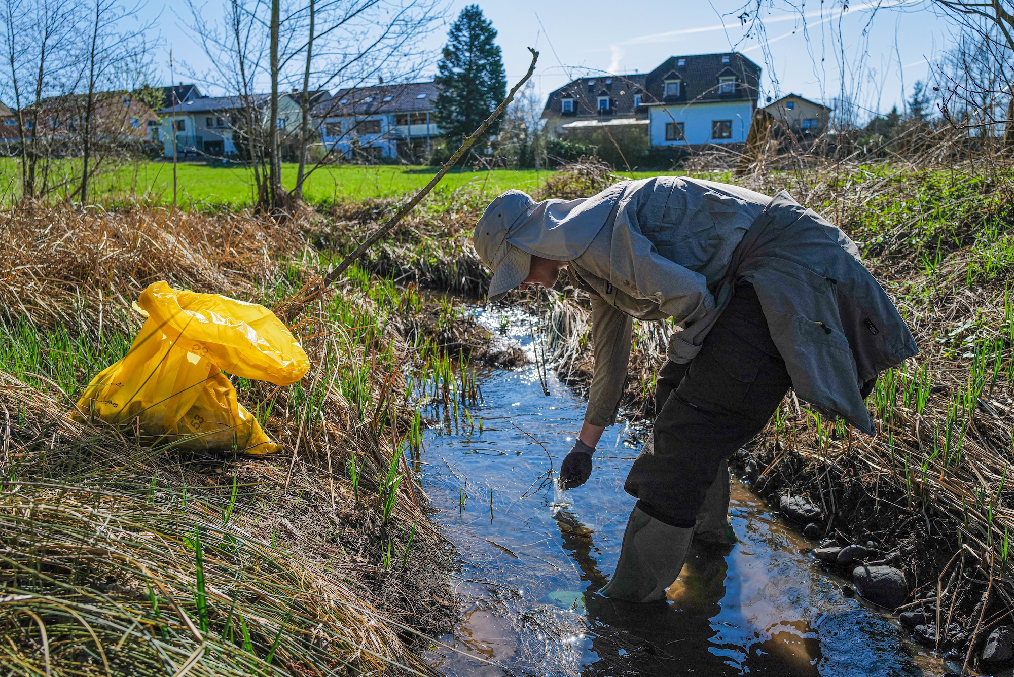 A member of the 52nd Civil Engineer Squadron Environmental Office collects a piece of plastic from a tributary of the Spanger Bach stream in Spangdahlem, Germany, April 5, 2025. Cleanup efforts focused on preventing litter from entering local waterways