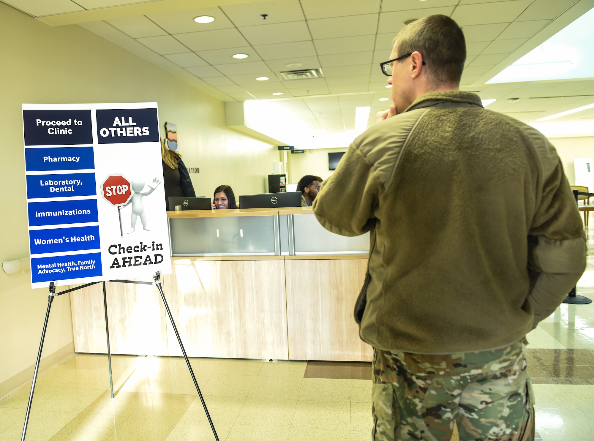 An Airmen reads a poster after the grand opening of the new central check in desk at 55th Medical Group Ehrling Berquist Medical Clinic.